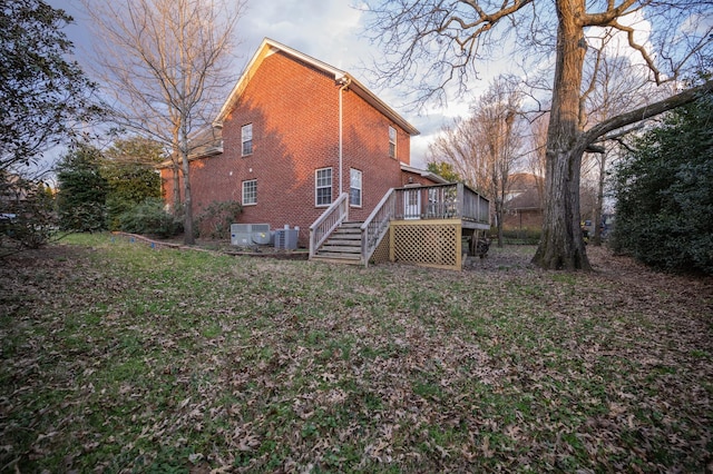 back of property with stairway, central AC unit, brick siding, and a wooden deck