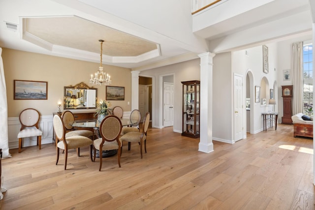 dining area with a raised ceiling, visible vents, and light wood-type flooring