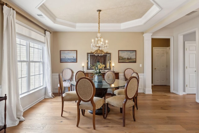 dining space featuring visible vents, a chandelier, a wainscoted wall, a tray ceiling, and light wood-style floors