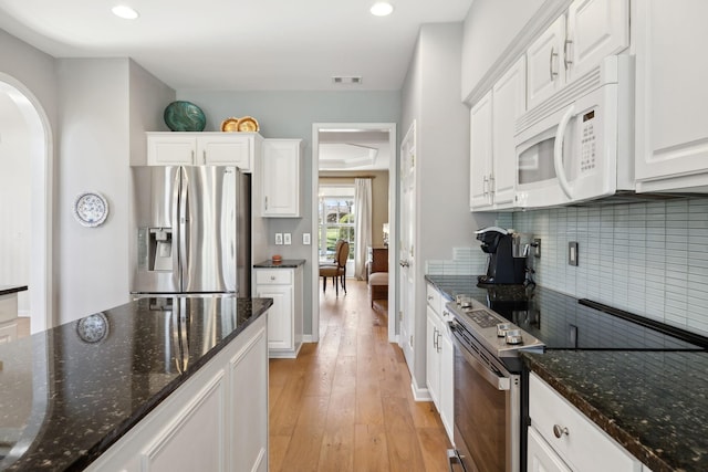 kitchen featuring light wood-type flooring, visible vents, stainless steel appliances, white cabinets, and decorative backsplash