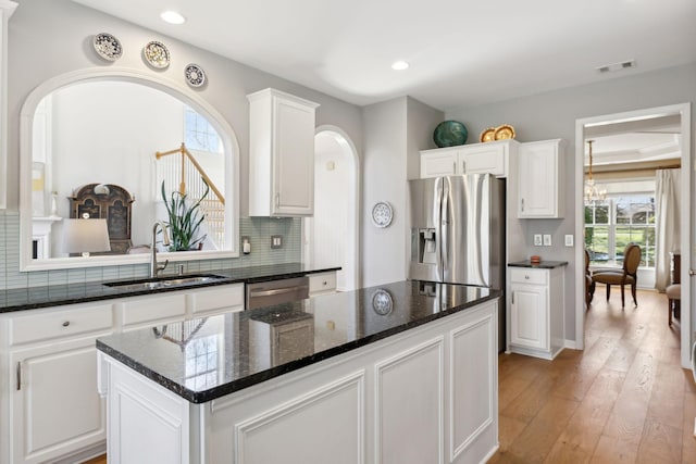 kitchen featuring tasteful backsplash, visible vents, appliances with stainless steel finishes, light wood-style floors, and a sink