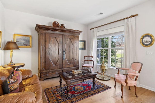 living area featuring visible vents, baseboards, and light wood-style floors