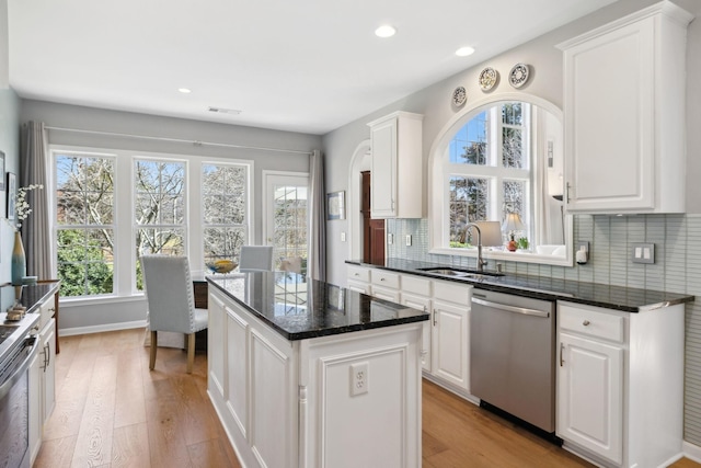 kitchen with dishwasher, a kitchen island, light wood finished floors, and a sink