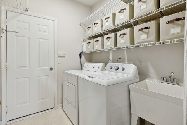 washroom with washer and dryer, light tile patterned flooring, laundry area, and a sink