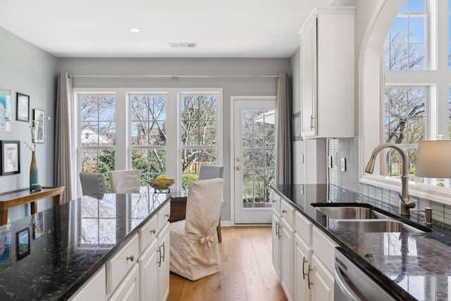 kitchen with visible vents, light wood-style flooring, a sink, tasteful backsplash, and white cabinetry