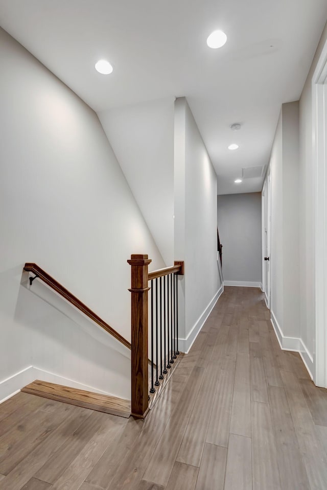 hall with recessed lighting, an upstairs landing, wood finished floors, and baseboards