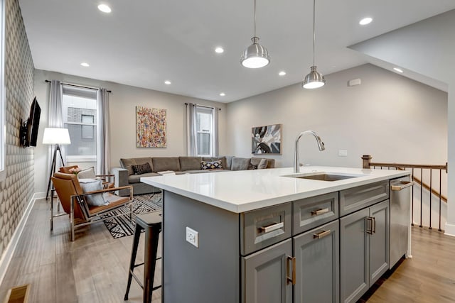 kitchen with a sink, light wood-type flooring, gray cabinets, and light countertops