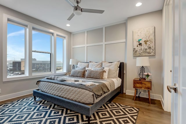 bedroom featuring a decorative wall, recessed lighting, baseboards, and wood finished floors