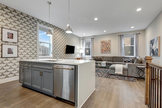 kitchen with light wood-type flooring, gray cabinetry, a sink, open floor plan, and dishwasher