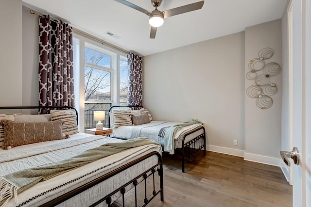 bedroom featuring a ceiling fan, wood finished floors, visible vents, and baseboards