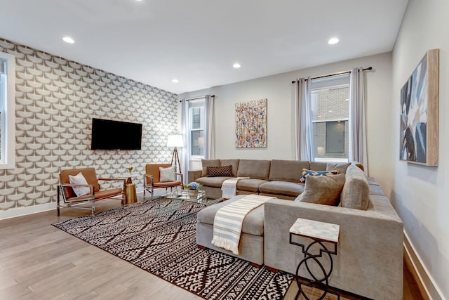 living area featuring wallpapered walls, an accent wall, baseboards, recessed lighting, and wood finished floors