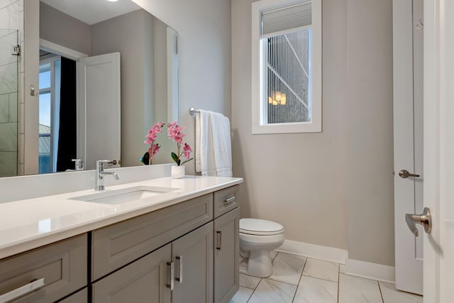 bathroom featuring baseboards, toilet, marble finish floor, and vanity