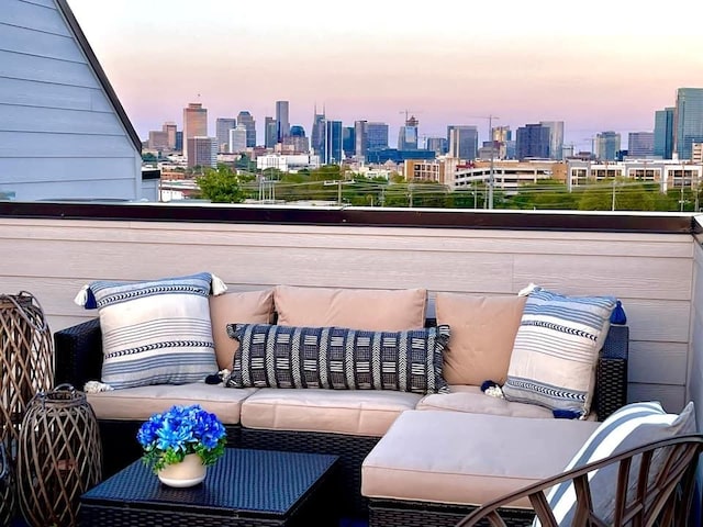 balcony at dusk featuring a city view and an outdoor hangout area