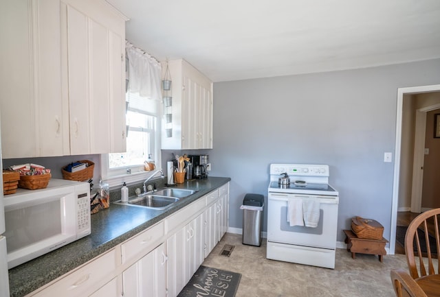 kitchen featuring dark countertops, baseboards, white cabinets, white appliances, and a sink