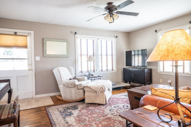 living area featuring baseboards, wood finished floors, and ceiling fan