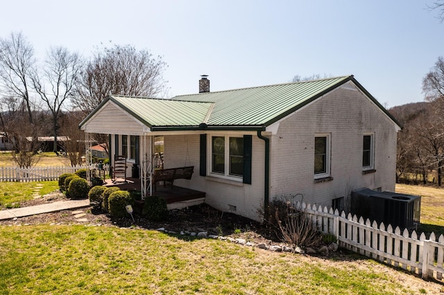 view of front of home featuring metal roof, brick siding, a chimney, and fence