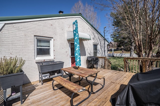 wooden deck with outdoor dining area, grilling area, and fence