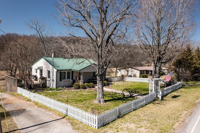 view of front facade with a front lawn, a fenced front yard, and metal roof