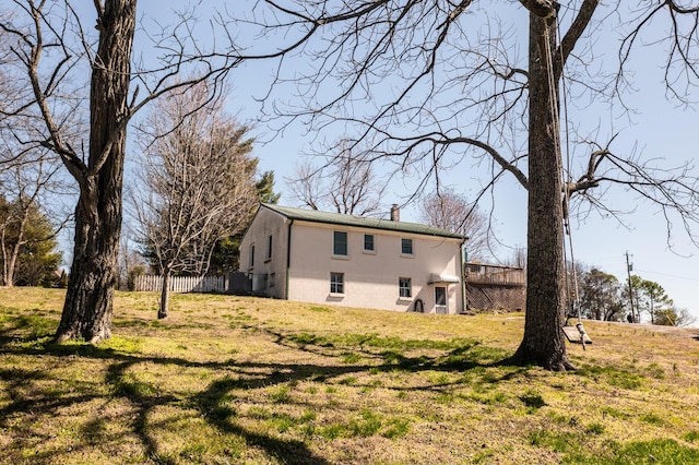 back of property with fence, a lawn, and a chimney