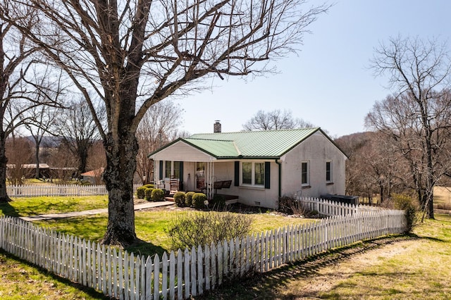 view of front facade with a fenced front yard, covered porch, a front yard, metal roof, and a chimney