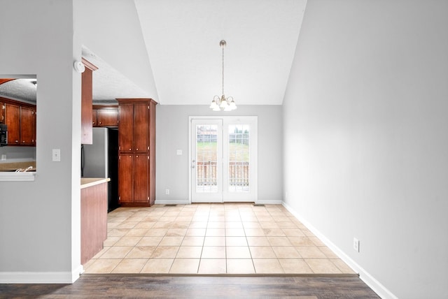 interior space with light tile patterned floors, baseboards, lofted ceiling, and an inviting chandelier