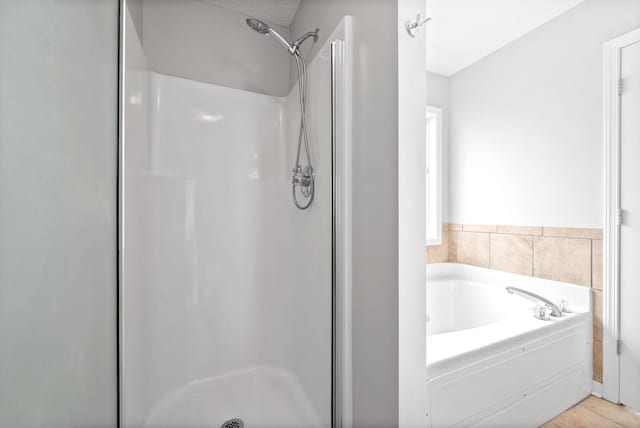 bathroom featuring tile patterned flooring, a shower stall, and a bath