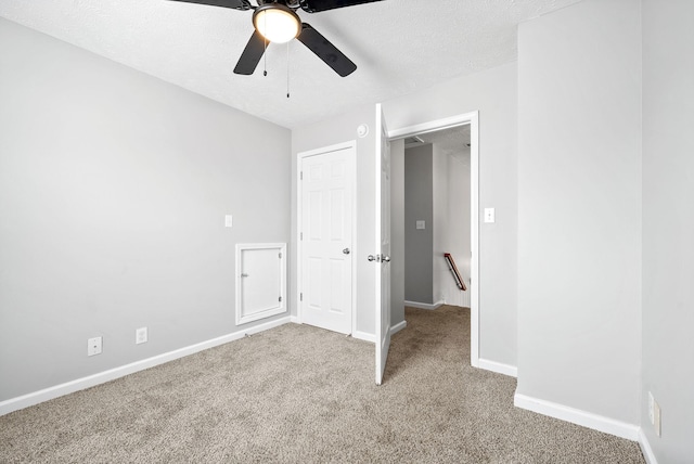 unfurnished bedroom with a ceiling fan, baseboards, carpet floors, and a textured ceiling