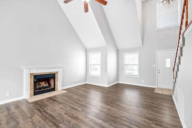 unfurnished living room featuring stairs, dark wood-type flooring, ceiling fan, and a fireplace