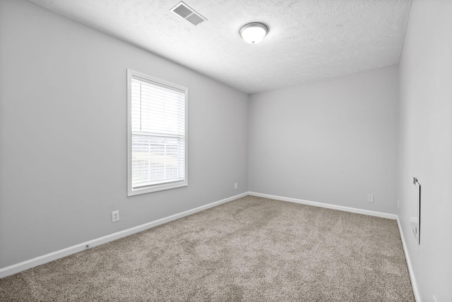 carpeted empty room with visible vents, a textured ceiling, and baseboards