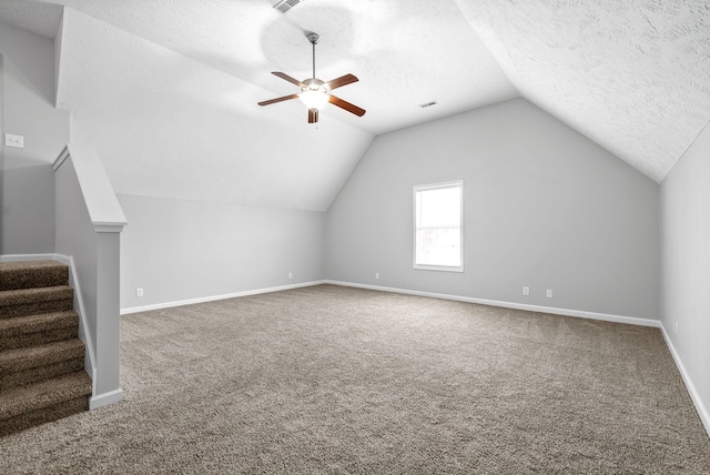 additional living space featuring baseboards, lofted ceiling, carpet floors, a textured ceiling, and a ceiling fan