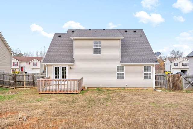 rear view of house featuring a deck, a lawn, roof with shingles, and a fenced backyard