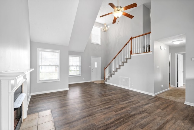 unfurnished living room featuring wood finished floors, a ceiling fan, visible vents, a fireplace with flush hearth, and stairs