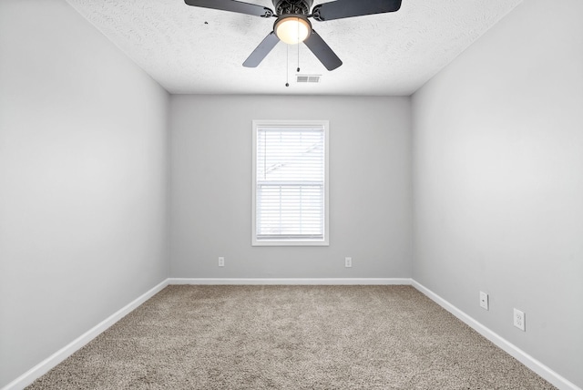 carpeted spare room with a textured ceiling, baseboards, visible vents, and ceiling fan