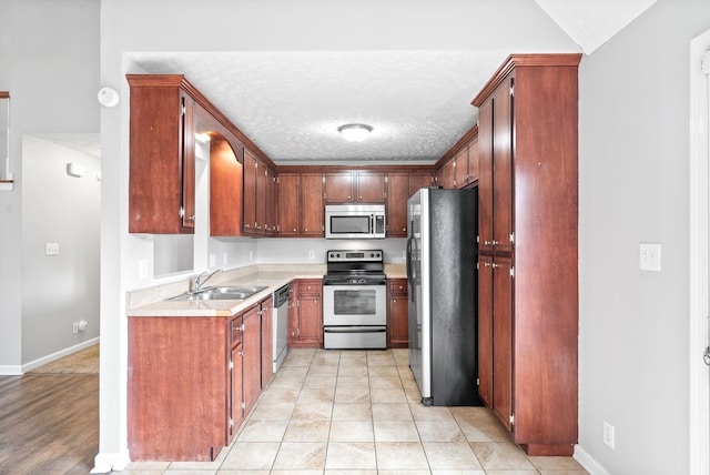 kitchen featuring light tile patterned floors, a sink, stainless steel appliances, light countertops, and a textured ceiling