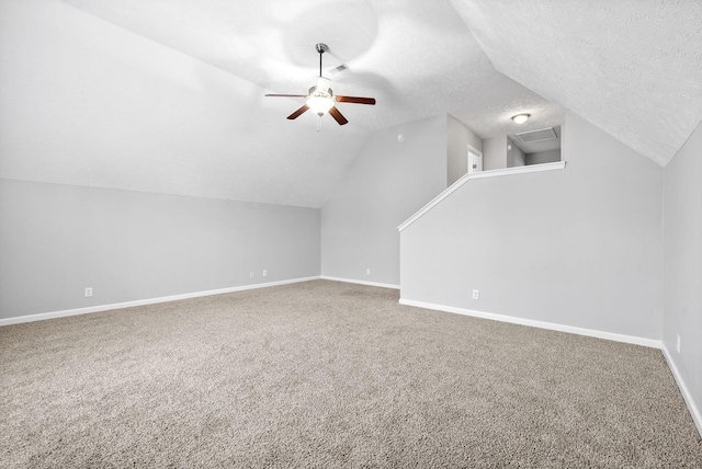 additional living space featuring a ceiling fan, a textured ceiling, carpet, baseboards, and vaulted ceiling