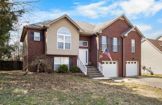 split foyer home featuring brick siding, an attached garage, concrete driveway, and fence