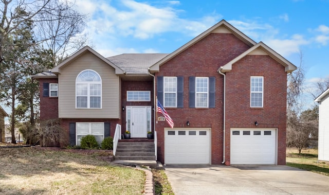 raised ranch featuring a garage, brick siding, and driveway