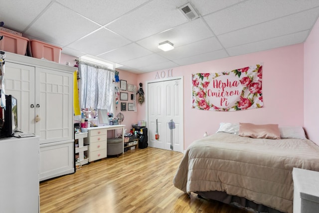 bedroom featuring a paneled ceiling, visible vents, and light wood finished floors