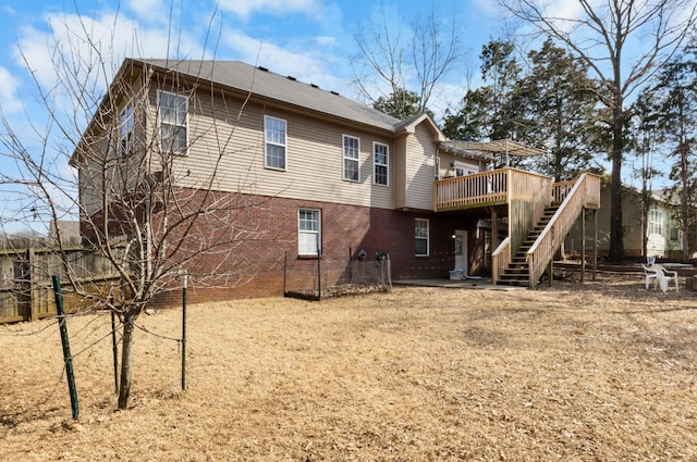 back of house featuring brick siding, a wooden deck, and stairs