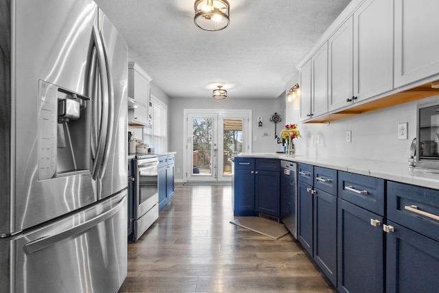 kitchen with white cabinetry, blue cabinetry, dark wood-style floors, and stainless steel appliances