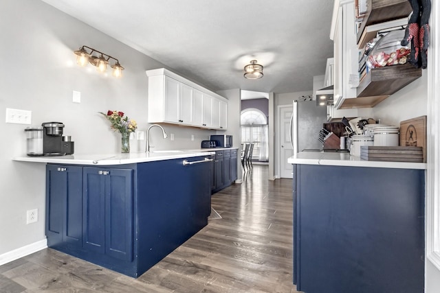 kitchen with baseboards, blue cabinetry, light countertops, dark wood-type flooring, and white cabinets