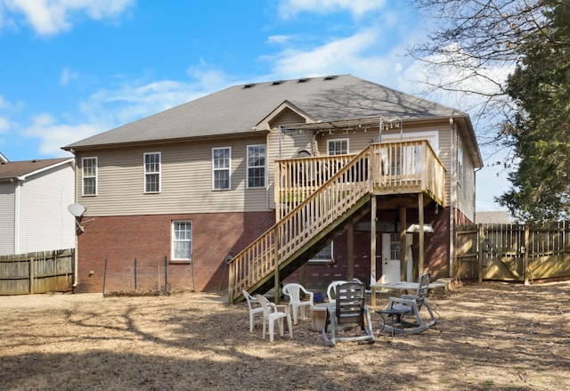 rear view of house with a deck, fence, stairway, a fire pit, and brick siding