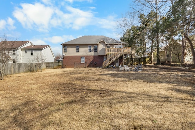 rear view of property featuring brick siding, a deck, stairs, and fence