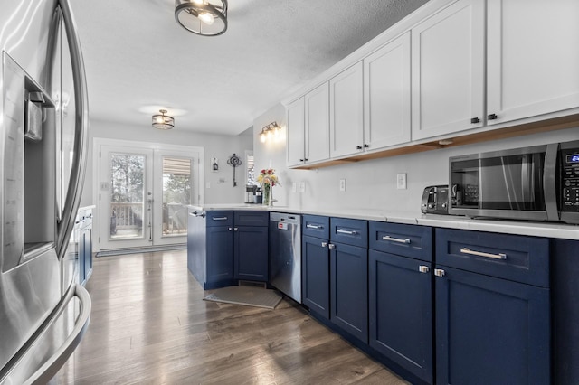 kitchen with blue cabinetry, dark wood-style floors, white cabinetry, appliances with stainless steel finishes, and light countertops