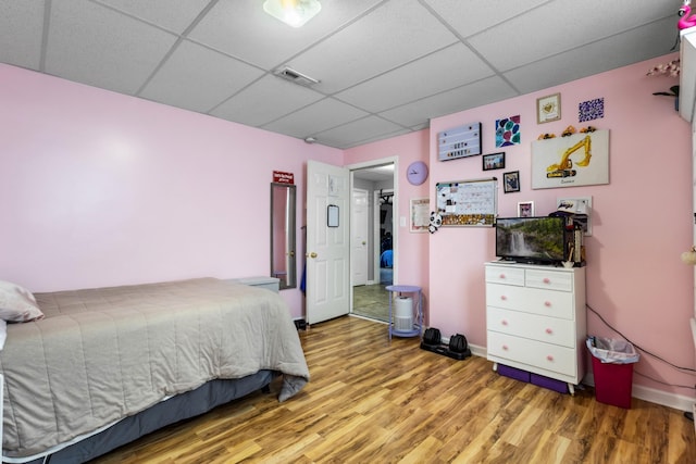 bedroom with visible vents, a paneled ceiling, and wood finished floors