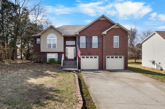 raised ranch featuring a garage, brick siding, concrete driveway, and a front lawn