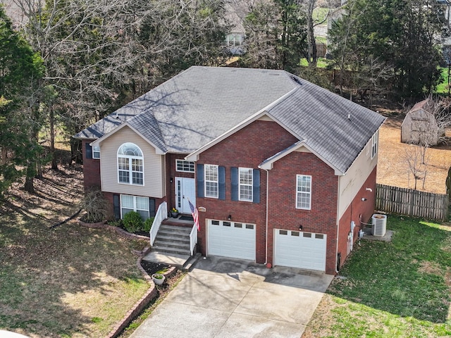 split foyer home featuring concrete driveway, fence, a garage, and roof with shingles