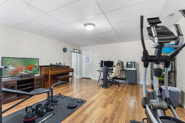 workout room with a drop ceiling, baseboards, and wood finished floors