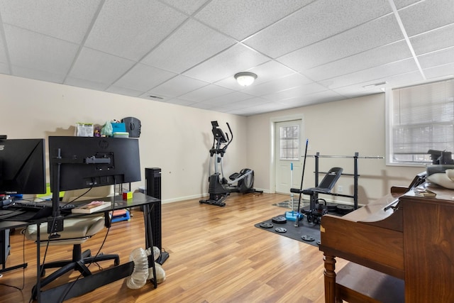 workout area with a drop ceiling, baseboards, and wood finished floors