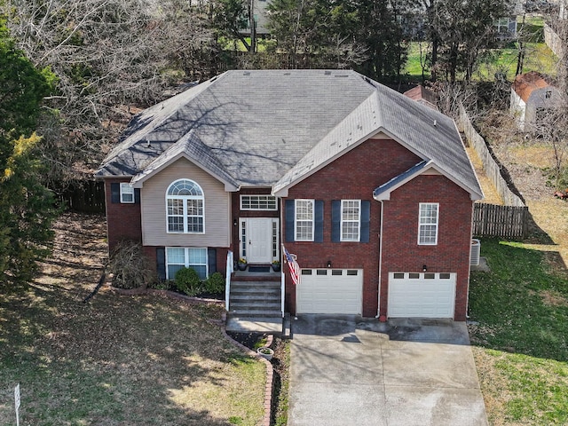 view of front facade featuring concrete driveway, an attached garage, fence, and brick siding